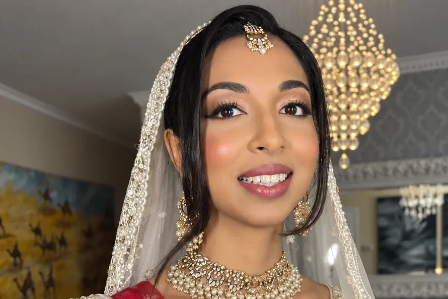 Bride in red and gold bridal lehenga with full bridal hair and makeup